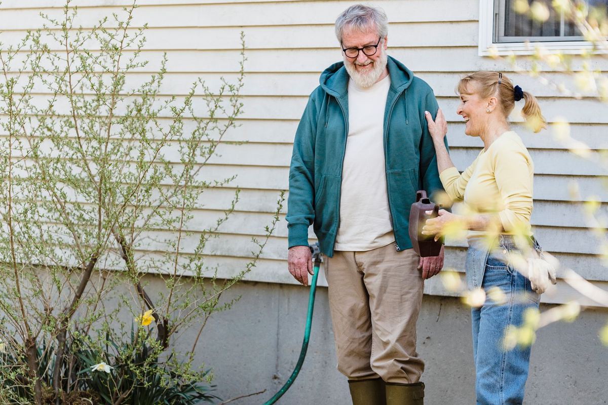 An older man and a younger woman working side by side in a garden